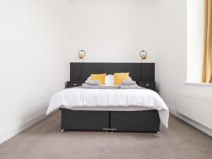 1 dormitorio con cama negra y almohadas amarillas en 1 Regents Mews, en Penzance
