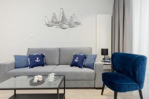 een woonkamer met een bank en een blauwe stoel bij Apartamenty Sunset Resort by Renters in Grzybowo