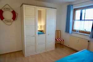 einen weißen Schrank in einem Schlafzimmer mit einem Bett und einem Fenster in der Unterkunft Kajüte 5 in Dahme