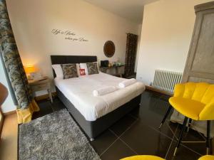 a bedroom with a bed and a yellow chair at OYO The Old Mill in Yarm