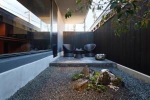 a courtyard with three chairs and a tree at HOTEL KYOTOLOGY in Kyoto