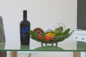 un tazón de verduras en una mesa con una botella de vino en Andrea Apartments, en Trogir