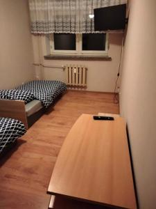 Habitación con 2 camas y mesa de madera. en Noclegi nad Parsętą 2, en Białogard