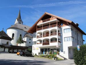 Holiday apartment in Leogang near the ski area في ليوغانغ: مبنى أبيض كبير مع كنيسة في الخلفية