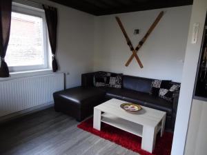 ein Wohnzimmer mit einem schwarzen Sofa und einem Tisch in der Unterkunft Apartment in Sonnenalpe am Nassfeld in Carinthia in Sonnenalpe Nassfeld