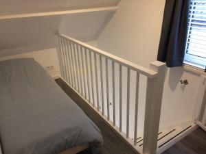 1 dormitorio con escalera, cama y ventana en Zomerhuis Zuid 1, en Egmond aan Zee