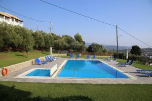 a swimming pool in a yard with lounge chairs around it at Villa Argiris in Agios Stefanos