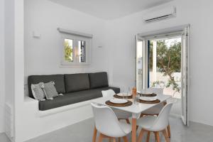a white living room with a black couch and a table and chairs at 21 luxury apartments in Naousa