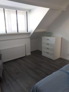 Un dormitorio abuhardillado con una cama, una cómoda y dos ventanas. en Zomerhuis Zuid 1, en Egmond aan Zee 2 fotos más