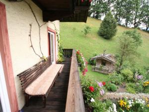 a wooden bench sitting on a porch with flowers at Huge Holiday Home in Hopfgarten im Brixental near Ski Lift in Hopfgarten im Brixental