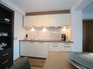 una cocina con armarios blancos y fregadero en Apartment in Westendorf Tyrol with terrace, en Westendorf