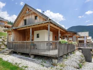 une maison en bois avec une terrasse couverte et une clôture dans l'établissement Wooden chalet in Hohentauern Styria with sauna, à Hohentauern