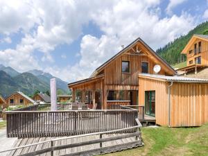 a wooden house with a deck and mountains in the background at Wooden chalet in Hohentauern Styria with sauna in Hohentauern