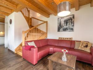 a living room with a red couch and a wooden staircase at Chalet in Carinthia near ski area in Kötschach