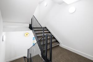 un escalier avec des balustrades noires et des murs blancs dans l'établissement Belmore 1 & 2 Bedroom Luxury Apartments with Parking in Stanmore, North West By 360 Stays London, à Stanmore