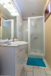 ein weißes Bad mit einem Waschbecken und einer Dusche in der Unterkunft Les Hirondelles in Pesmes