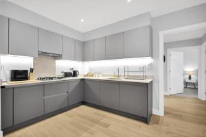 a kitchen with gray cabinets and a white counter top at Belmore 1 & 2 Bedroom Luxury Apartments with Parking in Stanmore, North West By 360 Stays London in Stanmore