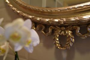 a gold mirror with white flowers in a vase at Villa Della Certosa in Gambassi Terme