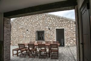 a wooden table and chairs in front of a stone wall at La Casa de Alarcón in Alarcón