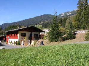 una casa en una colina con montañas en el fondo en Holiday home in Leogang in ski area, en Leogang