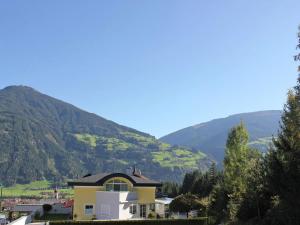 una casa amarilla con montañas en el fondo en Apartment in Ried im Zillertal with terrace en Ried im Zillertal