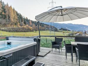 a deck with a hot tub and an umbrella at Chalet in St Georgen ob Murau with sauna in Sankt Georgen ob Murau