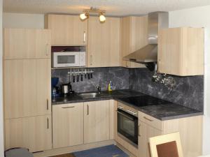 eine Küche mit Holzschränken, einer Spüle und einer Mikrowelle in der Unterkunft Apartment at Nassfeld in Carinthia in Sonnenalpe Nassfeld