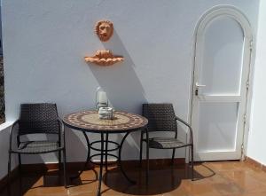 una mesa con tres sillas y una máscara en una pared en Casa Caldera Guiguan, en Tinajo