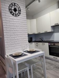 een keuken met een witte tafel en stoelen en een klok bij Apartament Piątka in Płock