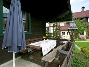 um pátio com uma mesa e um guarda-chuva azul em Chalet in Leogang Salzburg with garden em Leogang