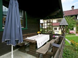 eine Terrasse mit einem Tisch und einem blauen Sonnenschirm in der Unterkunft Chalet in Leogang Salzburg with garden in Leogang