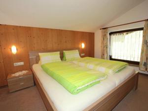 ウダーンスにあるSplendid Apartment in Fugen near Ski Areaのベッドルーム1室(大型ベッド1台、黄色と緑のシーツ付)