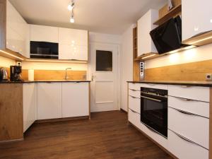 a kitchen with white cabinets and a black oven at Holiday home near Zell am See and Kaprun in Bruck an der Großglocknerstraße