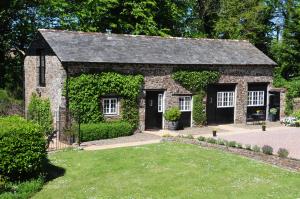 um pequeno edifício de pedra com um quintal em frente em Cloister Park Cottages em Frithelstock
