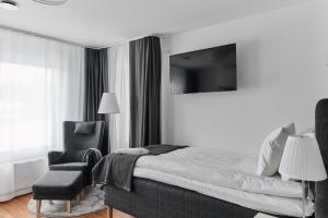 a bedroom with a bed and a chair and a television at Continental Apartment Hotel Knivsta in Knivsta