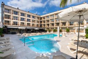 a hotel with a swimming pool with chairs and an umbrella at Aparthotel Miami Park in Calella