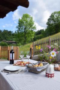 - une table avec une assiette de nourriture et des verres à vin dans l'établissement Baita Meidlnhof, à Fierozzo