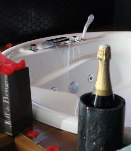 - une bouteille de champagne dans la baignoire avec une bouteille de vin dans l'établissement Seasides Paris - Suite Monroe, au Blanc-Mesnil