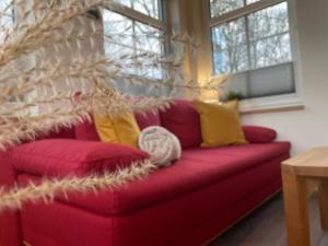 un sofá rojo con almohadas amarillas en la sala de estar. en Ferienwohnung Haus Peters "De olle Warkstee", en Elmlohe