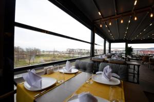 REF İNN HOTEL في أوردو: مطعم بطاولات وكراسي ونافذة كبيرة