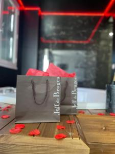 two bags sitting on top of a table with red flowers at Seasides Paris - Suite Monroe in Le Blanc-Mesnil