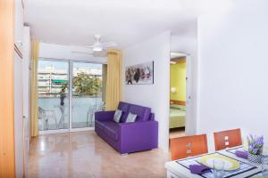 a living room with a purple chair and a table at Apartaments Costa d'Or in Calafell