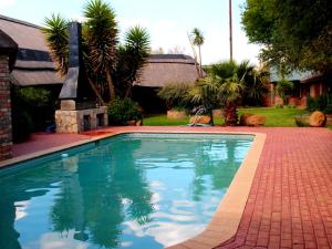 una piscina en un patio con una entrada de ladrillo en Boskoppie Lion & Tiger Reserve, en Kroonstad