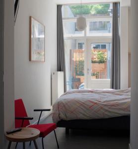 a bedroom with a bed and a window and a chair at B&B Central Park in Utrecht