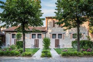 ein Steinhaus mit Bäumen und Blumen in der Unterkunft Isola Verde Resort in Castiglione del Lago