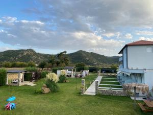 a yard with a building and mountains in the background at A Ponte Studios & Apartments in Sykia Chalkidikis