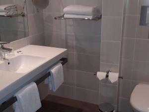 a bathroom with a sink and a toilet and towels at Mercure Dinan Port Le Jerzual in Dinan