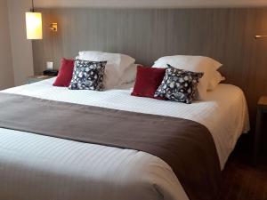 a large bed with pillows on it in a room at Mercure Dinan Port Le Jerzual in Dinan