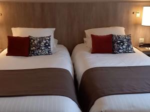 twee bedden naast elkaar in een kamer bij Mercure Dinan Port Le Jerzual in Dinan