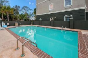 a swimming pool with a bench next to a building at La Quinta Inn & Suites by Wyndham Broussard - Lafayette Area in Broussard